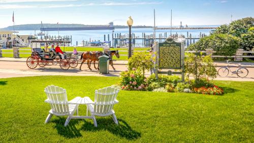 um parque com duas cadeiras e uma placa e uma carruagem puxada por cavalos em Island House Hotel em Mackinac Island