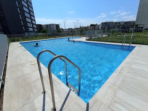 a large swimming pool with blue water in a city at Hermoso departamento con piscina, muy cerca del centro, playas, malls, hipermercado, hospital y clínicas in La Serena