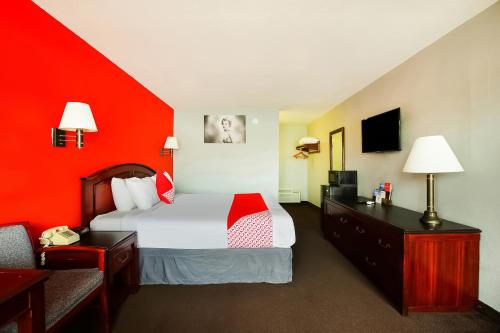 une chambre d'hôtel avec un lit et un mur rouge dans l'établissement OYO Hotel Texarkana North Heights AR Hwy I-30, à Texarkana