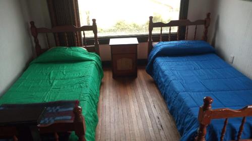 two beds sitting in a room with a window at Casa los Lobos a una cuadra de la playa El Quisco in El Quisco