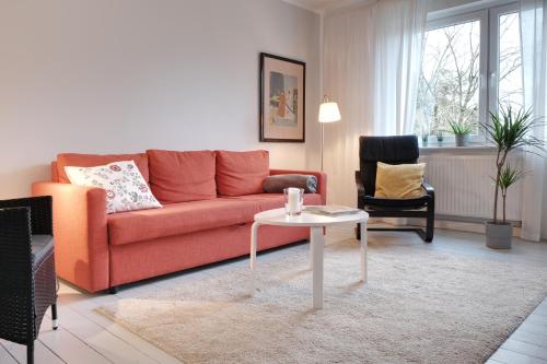 ein Wohnzimmer mit einem roten Sofa und einem Tisch in der Unterkunft Schicke & helle Wohnung in Mülheim an der Ruhr in Mülheim an der Ruhr