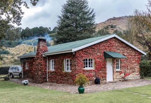 a red brick house with a car parked in front of it at Esigodini Cottage in Underberg