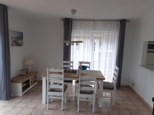 ein Esszimmer mit einem Tisch und weißen Stühlen in der Unterkunft Küstenhaus Duhnen - Erdgeschoss mit Terrasse in Cuxhaven