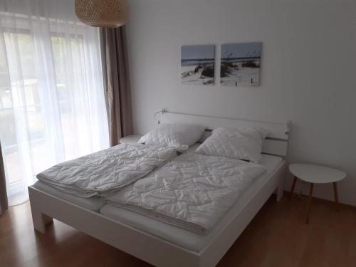 ein weißes Bett in einem Zimmer mit Fenster in der Unterkunft Küstenhaus Duhnen - Erdgeschoss mit Terrasse in Cuxhaven