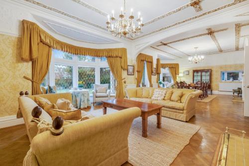 a large living room with yellow furniture and a chandelier at Blackpool Abode - Southlands in Blackpool