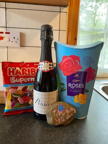 a bottle of wine and a bag of cookies on a counter at Pine Cabin, Strathyre. A cosy escape from it all. in Strathyre