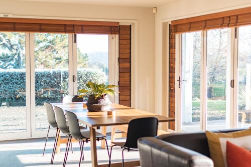 uma sala de jantar com mesa, cadeiras e janelas em Lavender Hill em Riverhead