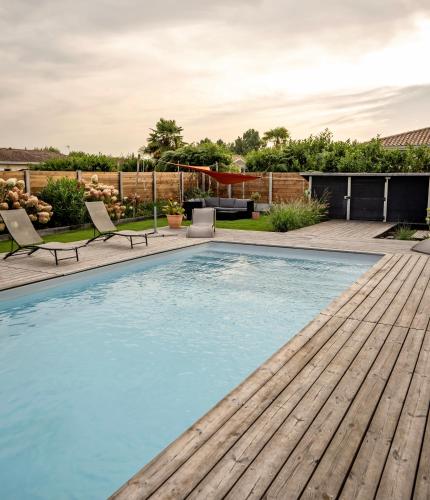 une piscine avec une terrasse en bois et une arrière-cour dans l'établissement EVASION BASSIN La Villa Albatros, à Lège