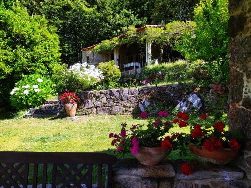 un giardino fiorito e un muro di pietra di O Lughar Darriba Fogar Natural a Gallardo