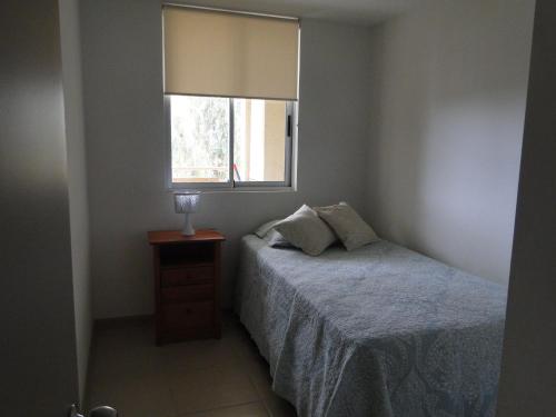 a small bedroom with a bed and a window at COSTA ALGARROBO in Algarrobo