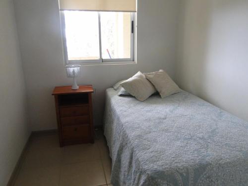 a small bedroom with a bed and a window at COSTA ALGARROBO in Algarrobo