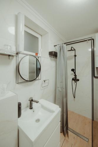 a white bathroom with a sink and a shower at Kućica in Đakovo