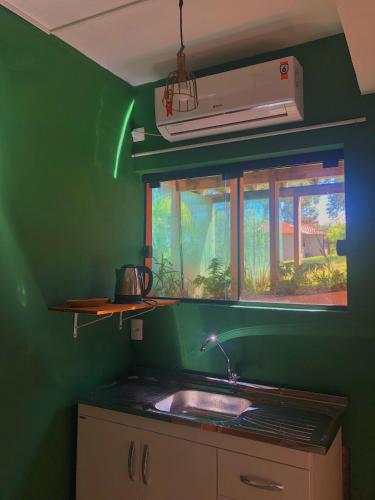 a green kitchen with a sink and a window at Sapê Guest Hotel in Praia do Rosa