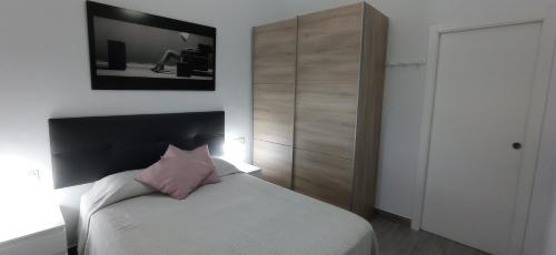 1 dormitorio con cama blanca y almohada rosa en Loft cerca del centro de Málaga, en Málaga