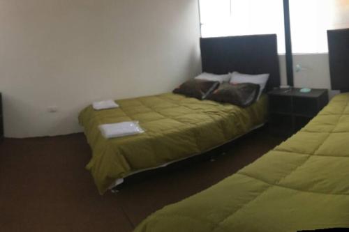 a bedroom with two beds with green comforters at Apartamento independiente x6 RegenWasi in Cusco