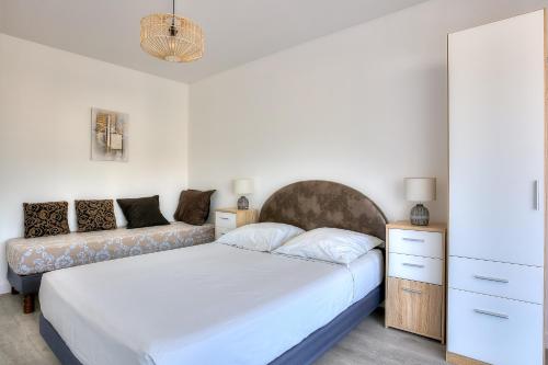 a bedroom with two beds and a couch at Le Sun-Beach - Spacieux 3 pièces avec parking à 400 m des plages de Juan-les-Pins in Juan-les-Pins