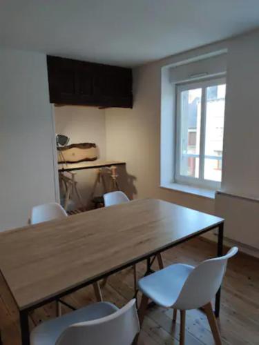 une table à manger avec des chaises blanches et une fenêtre dans l'établissement Le petit nid du Mont Saint Michel, à Pontorson