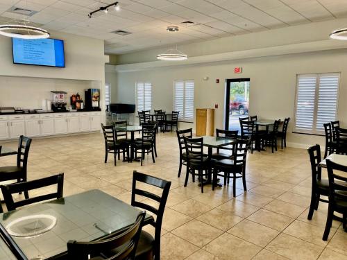 a dining room with tables and chairs and a kitchen at Days Inn & Suites by Wyndham Lakeland in Lakeland