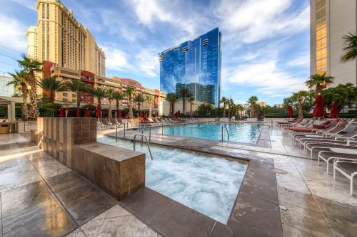 uma piscina com espreguiçadeiras e edifícios em Awesome The Signature MGM condo with Strip view. No resort fee! em Las Vegas