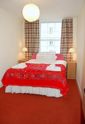 エディンバラにあるロイヤル マイル アパートメントのベッドルーム1室(赤いカーペット敷きの大型ベッド1台付)