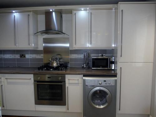 een keuken met witte kasten en een wasmachine bij Old Templars Cottage in Spittal