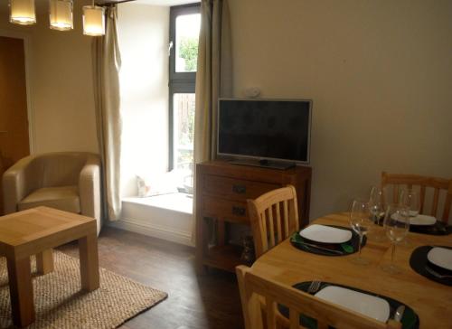 a living room with a table and a television at Old Templars Cottage in Spittal
