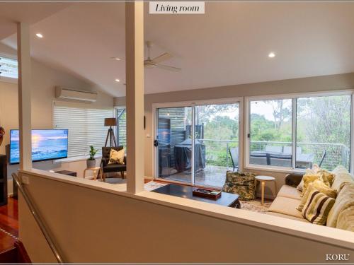 a living room with a large window and a couch at Koru at Hyams Beach in Hyams Beach