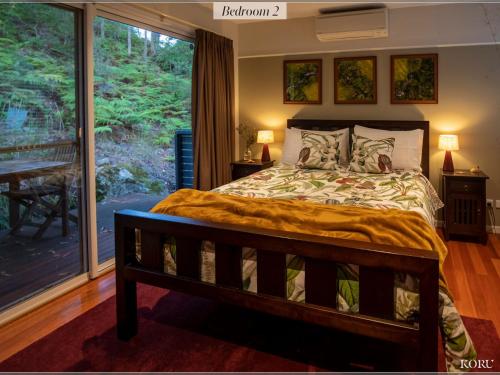 a bedroom with a bed and a large window at Koru at Hyams Beach in Hyams Beach