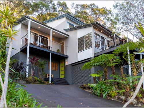 a white house with a lot of plants and trees at Koru at Hyams Beach in Hyams Beach