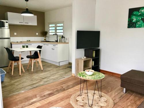 uma sala de estar com uma cozinha e uma mesa com uma televisão em Villas Smoothie Papaya em Le François