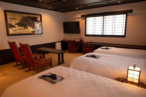 a hotel room with two beds and a table and a television at Kyoto Takasegawa Bettei in Kyoto