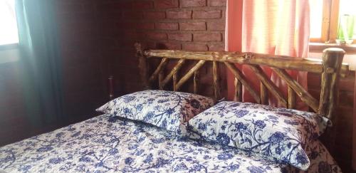 a bed with a wooden headboard and two pillows at Recanto do Leão in Alagoa