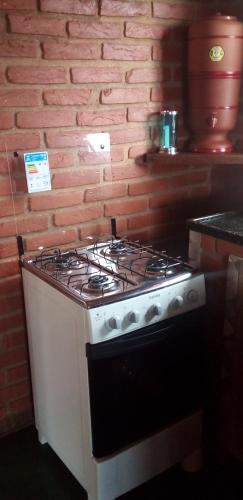 a stove in a kitchen with a brick wall at Recanto do Leão in Alagoa