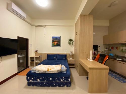 a bedroom with a blue bed and a kitchen at Loka B&B in Taitung City