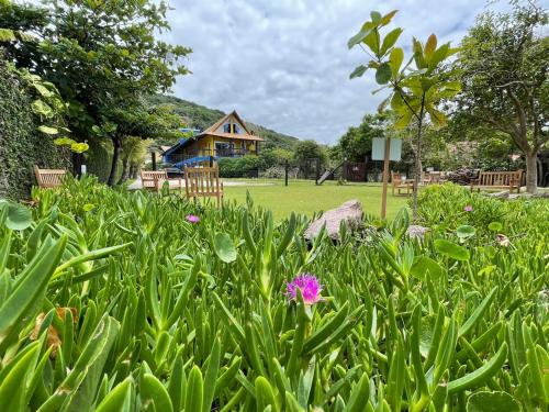 a garden with flowers and a house in the background at Penareia Floripa Beach Hotel in Florianópolis