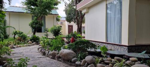 a garden with rocks and tables and a building at Vạn Huệ Homestay Bình Dương in Thuan An