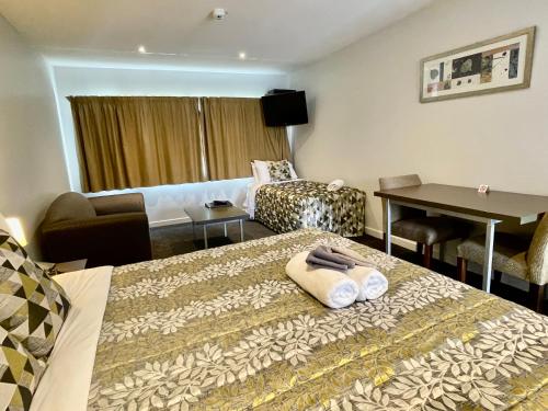 a hotel room with two beds and a desk at Airport Delta Motel in Christchurch