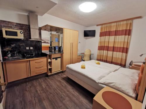 ein Hotelzimmer mit einem Bett und einer Küche in der Unterkunft Cesar's Pension in Föhrenhain