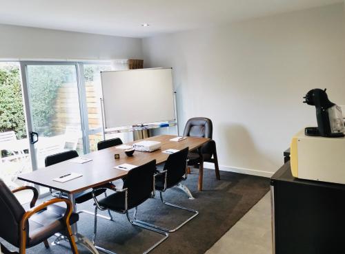 a conference room with a table and chairs and a whiteboard at Airport Delta Motel in Christchurch