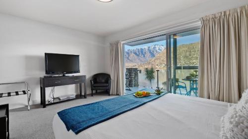 a bedroom with a large bed and a large window at Alpine Lakeside Studio in Queenstown