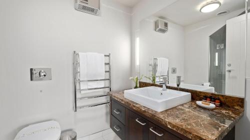 uma casa de banho branca com um lavatório e um WC em Alpine Lakeside Studio em Queenstown