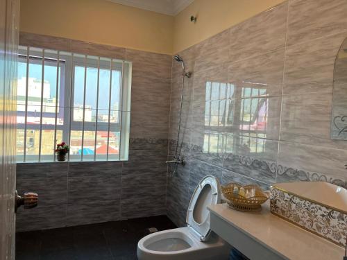 a bathroom with a toilet and a sink and a window at Queenwood Hotel in Phnom Penh