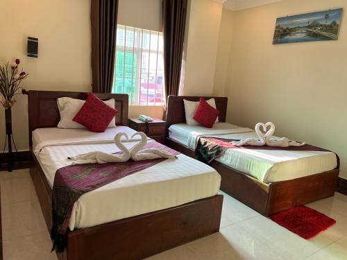 a hotel room with two beds with bows on them at Queenwood Hotel in Phnom Penh