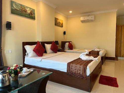 a hotel room with two beds and a table at Queenwood Hotel in Phnom Penh