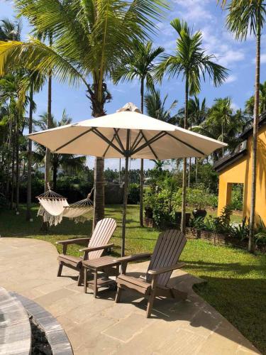 two chairs and a table with an umbrella and a hammock at La Siesta Hoi An Resort & Spa in Hoi An