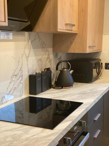 a kitchen with a stove and a tea kettle on a counter at Lovely 3 bed with jacuzzi, close to airport, driveway, wifi in Edinburgh