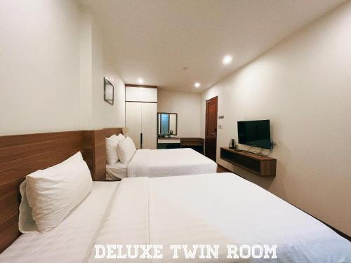 a hotel room with two beds and a television at Paragon House and Residence in Hanoi