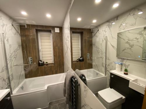 a bathroom with a tub and a toilet and a sink at Lovely 3 bed with jacuzzi, close to airport, driveway, wifi in Edinburgh