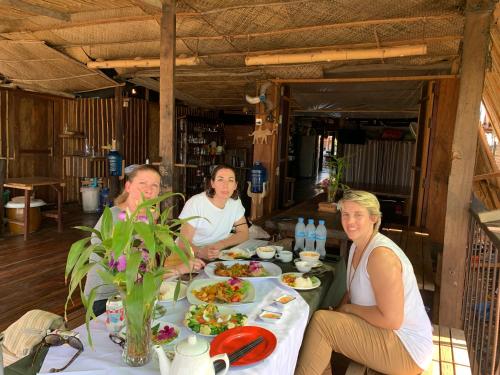 a group of people sitting at a table with food at ST 63 Home Stay & Tour Kampong Khleang in Kâmpóng Khleăng