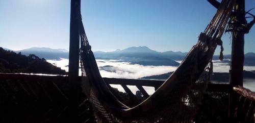 a hammock on top of a mountain with clouds at Recanto do Leão in Alagoa